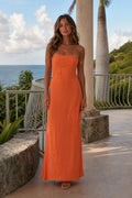 Front view of woman wearing orange strapless maxi dress outdoors
