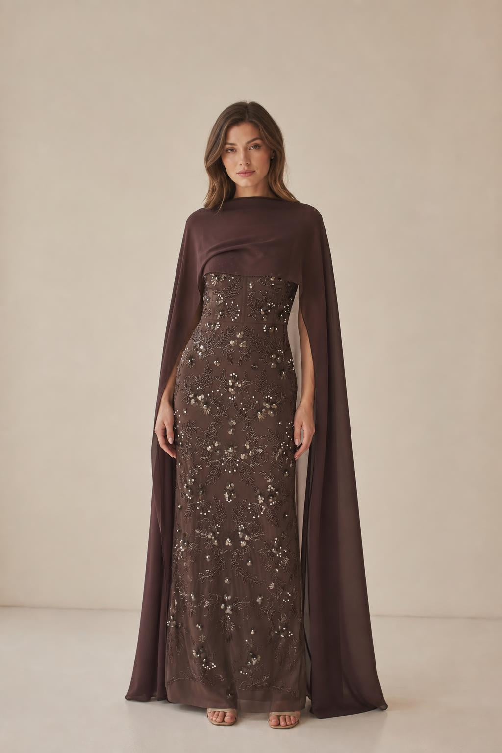 Front view of model wearing brown beaded maxi dress with cape