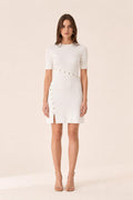 Front view of woman wearing white ribbed knit mini dress with gold buttons