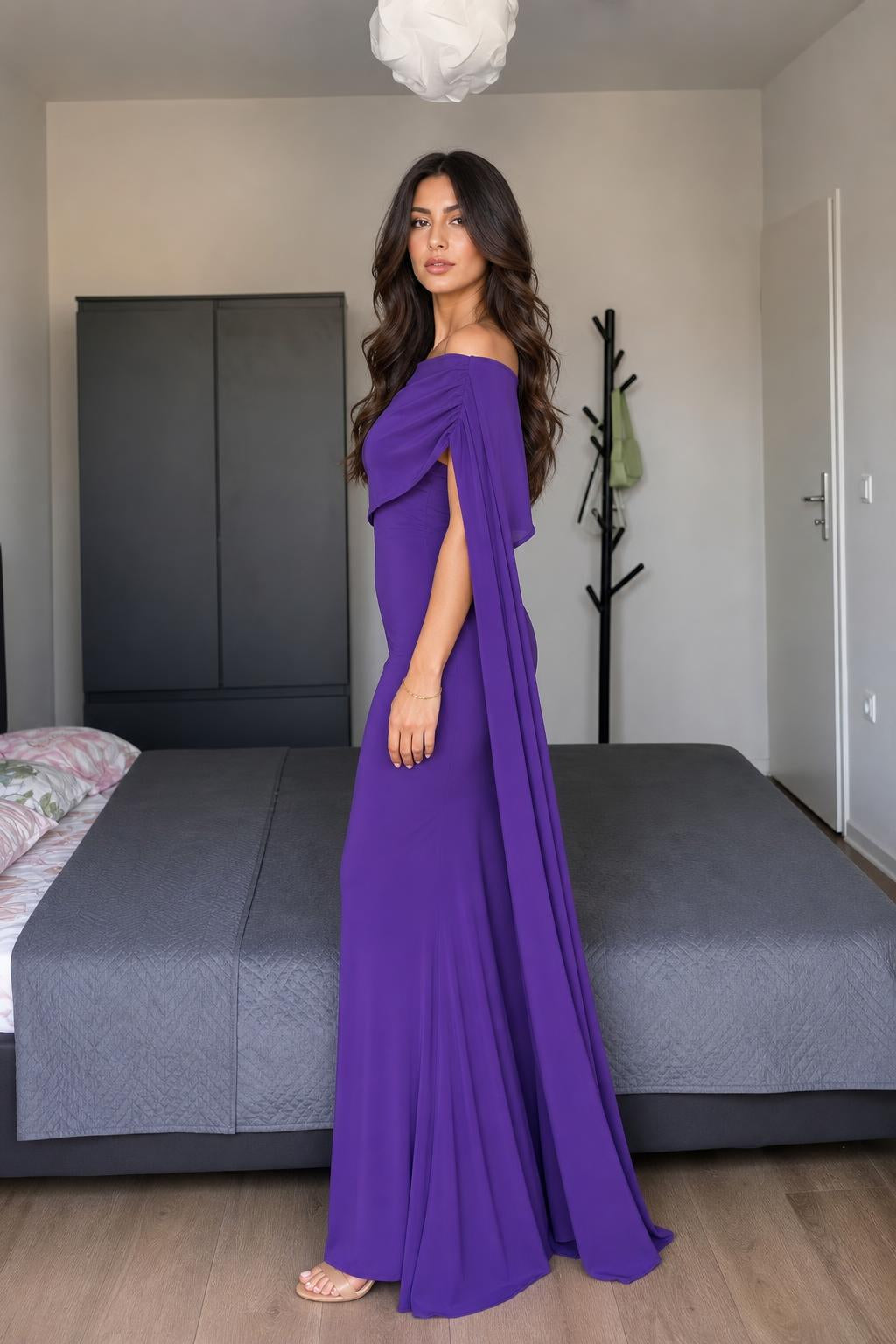 Model wearing purple off-shoulder cape maxi dress side view