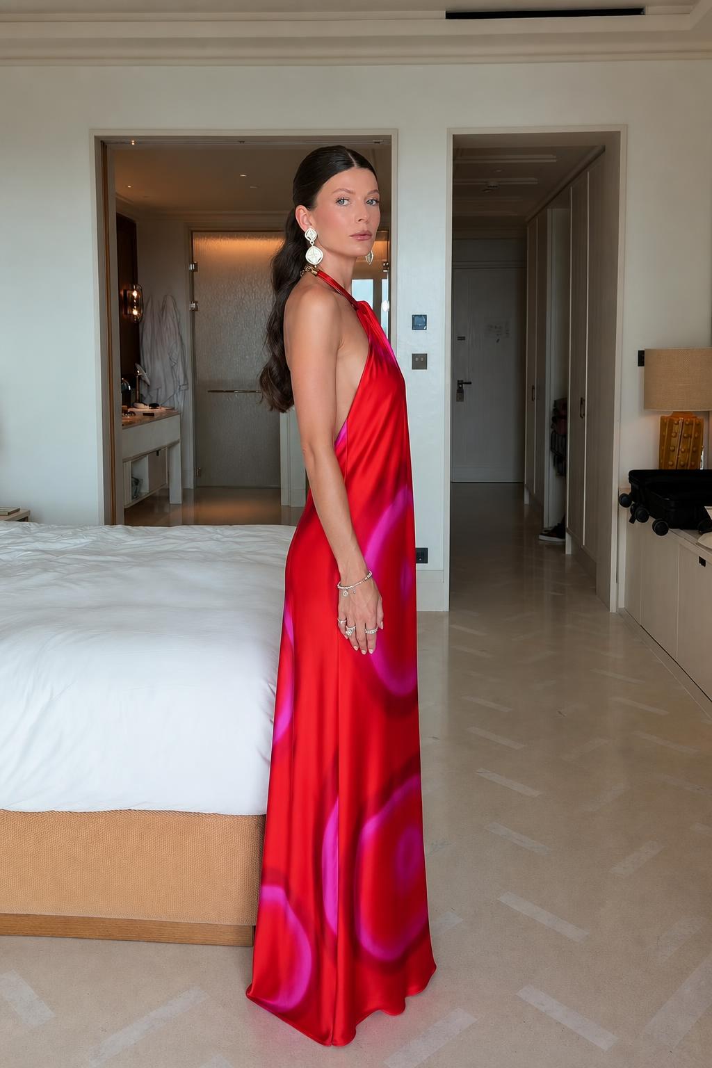 Side profile view of model in flowing red abstract print maxi dress