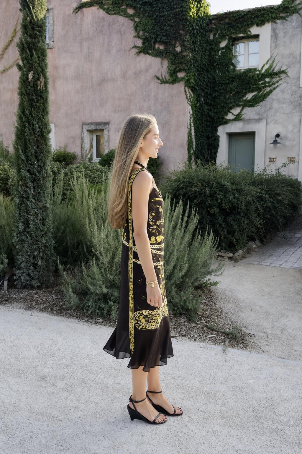 Model wearing black vintage gold print midi dress side view