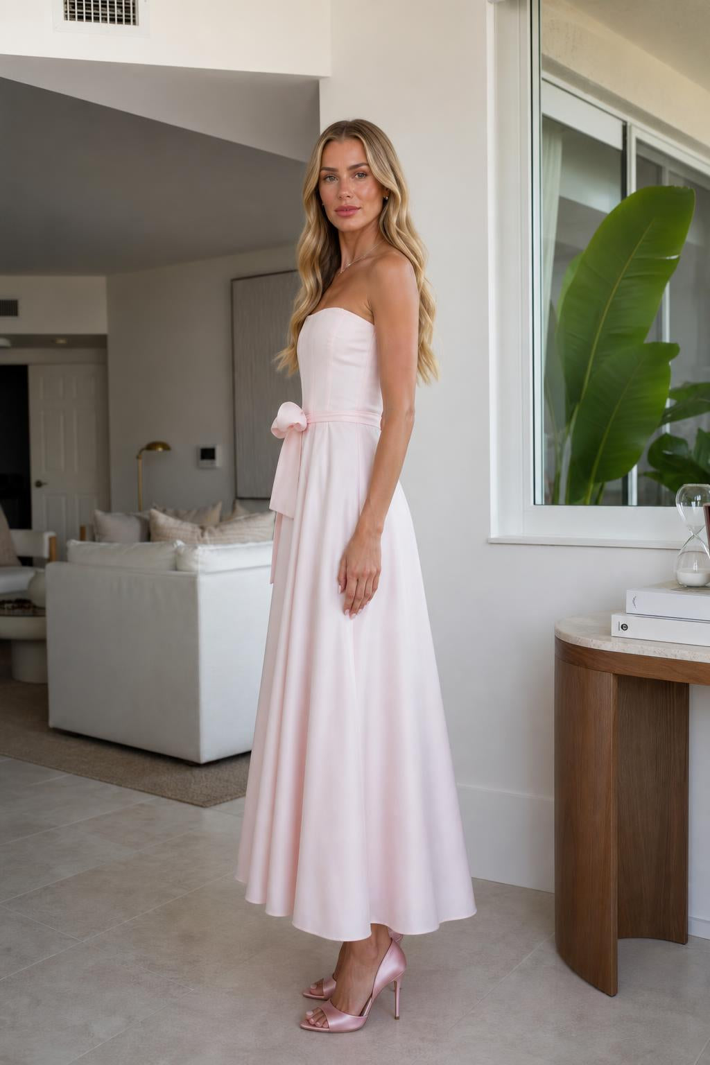 Model wearing pink strapless midi dress, side profile