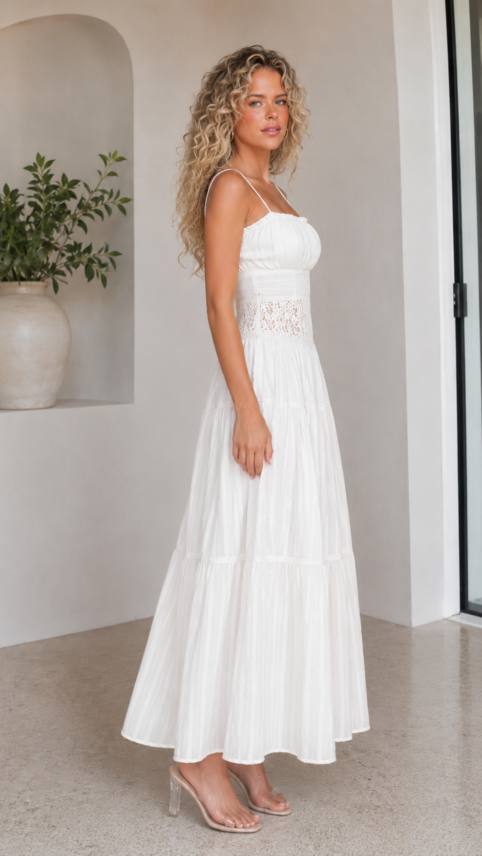 Side view of white pleated maxi dress with slim straps and tiered skirt