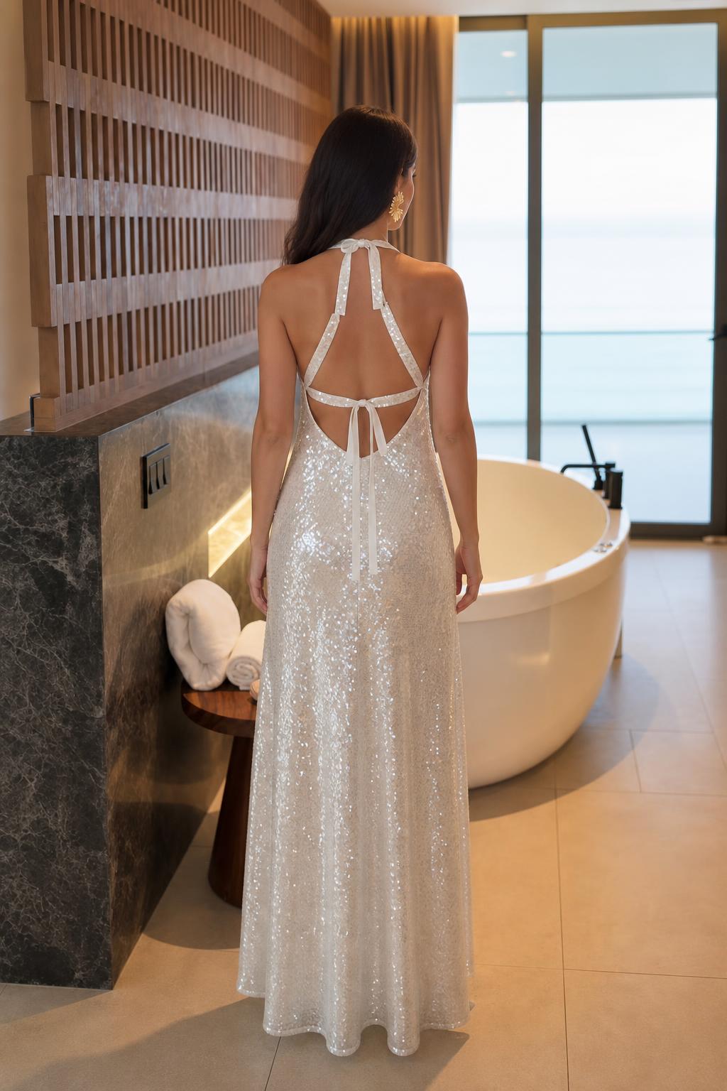 Model wearing white sequin halter maxi dress showing open back