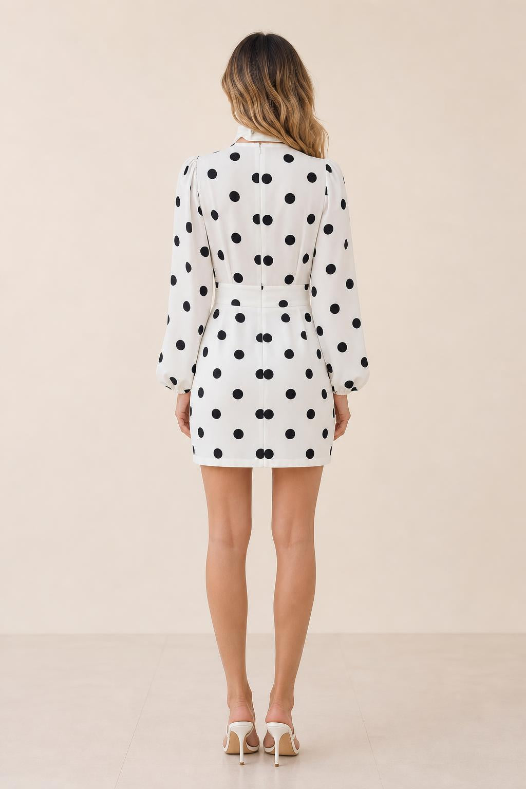 Back view of model in white polka dot mini dress