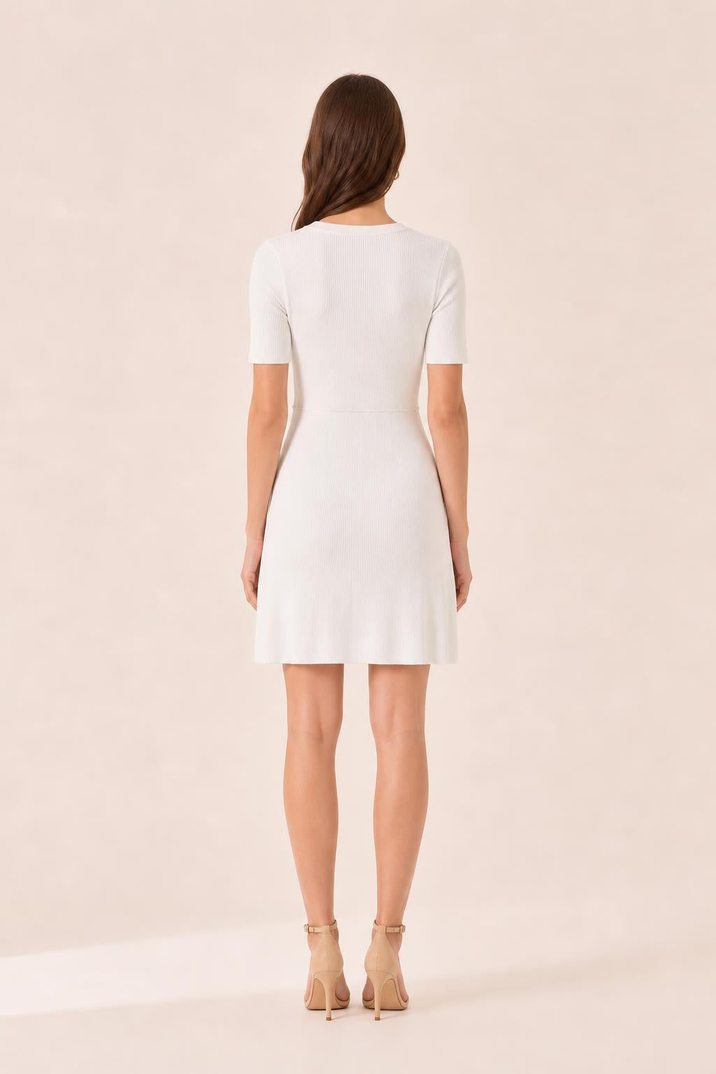 Back view of woman in white ribbed knit mini dress
