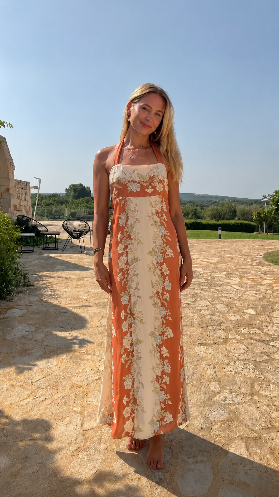 Model wearing coral and cream floral halter neck maxi dress full-length front view