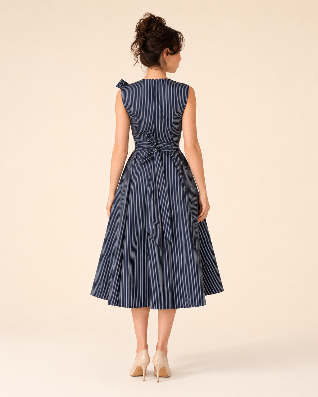 Back view of navy sleeveless striped midi dress with tie waist and flared midi skirt