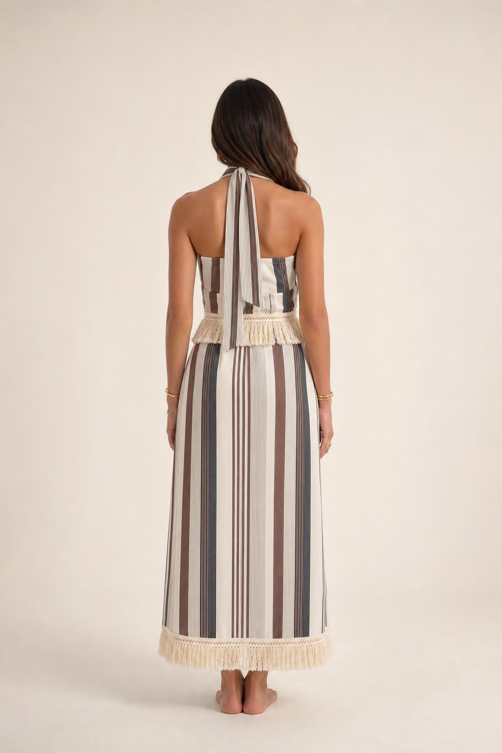 Back view of model wearing beige stripe halter fringe maxi dress