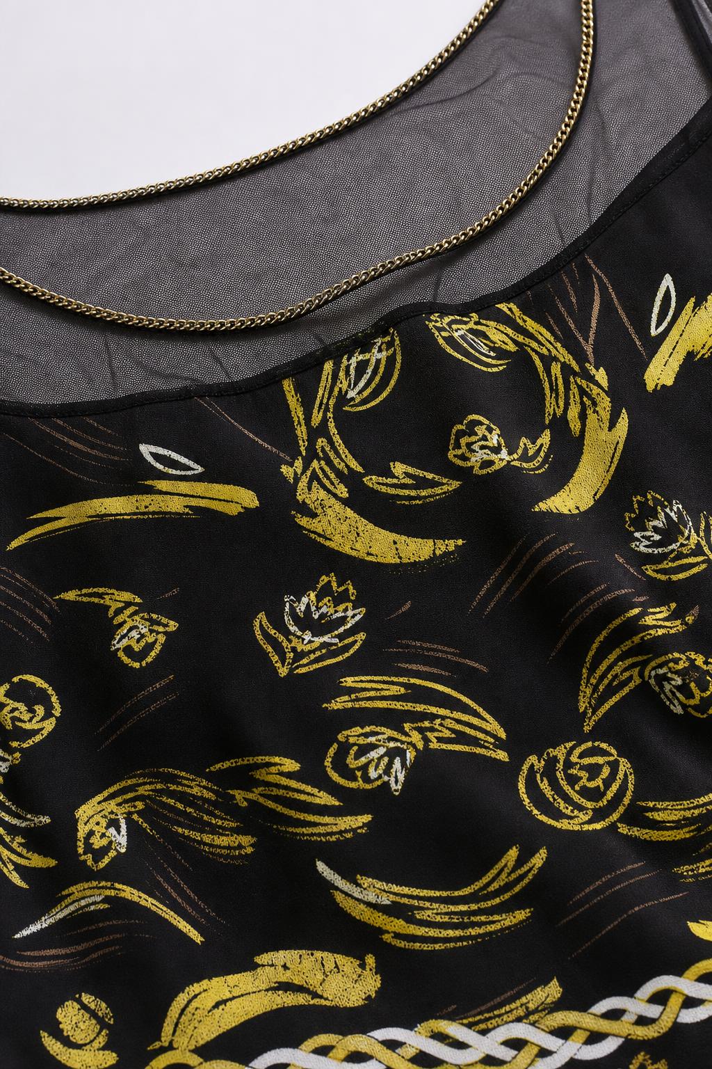 Close-up of sheer neckline with chain trim and gold print detail