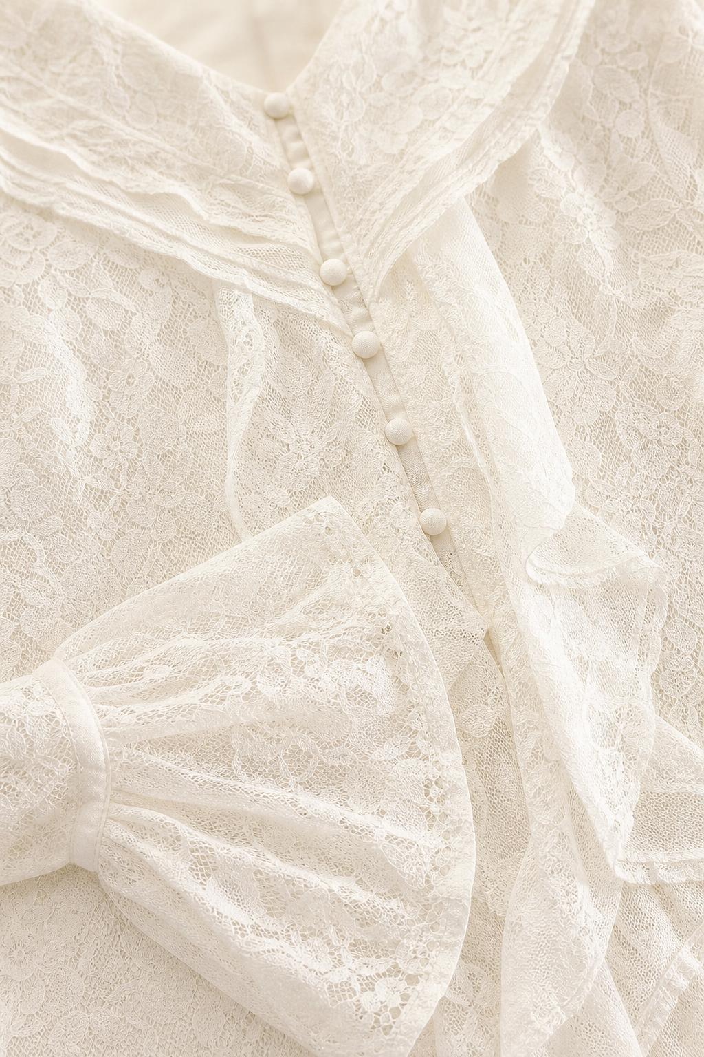 Close-up detail of lace texture, buttons, and ruffle trim on white dress
