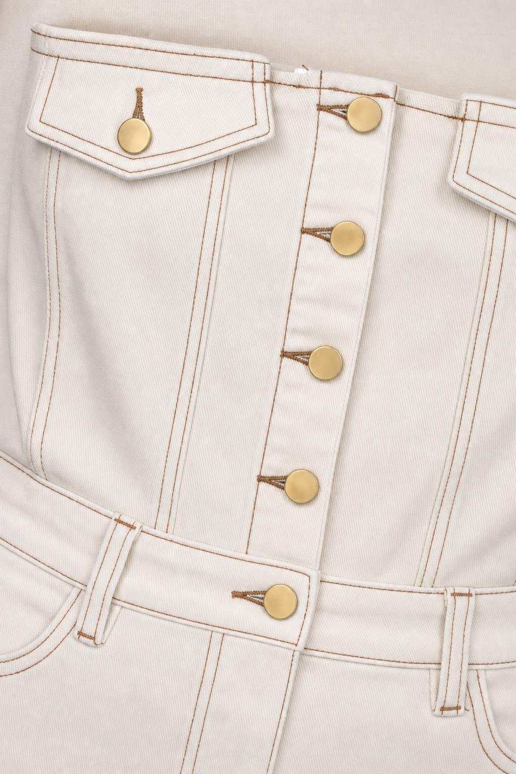 Close-up detail of white denim dress button placket and topstitching