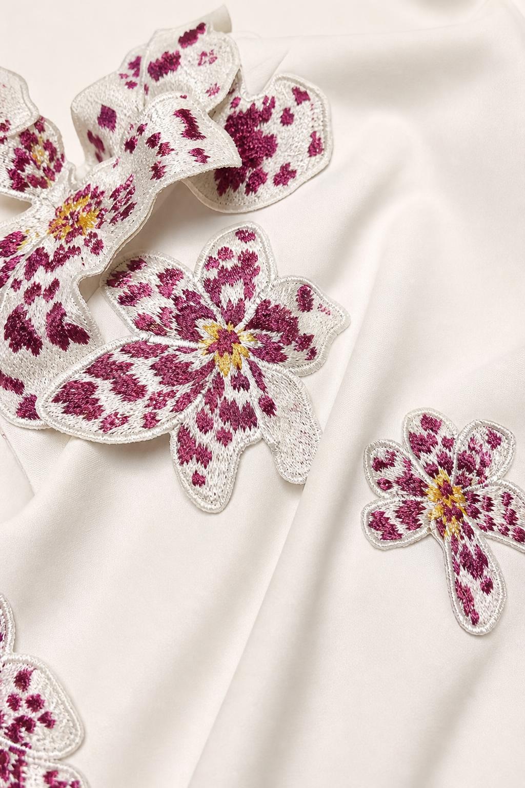 Close-up of 3D embroidered floral appliques on smooth white fabric