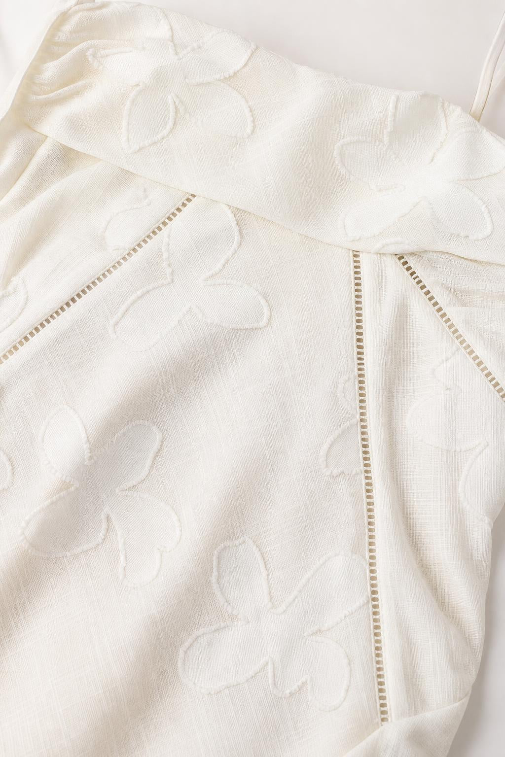 Close up fabric detail of tonal floral pattern and stitching on white dress