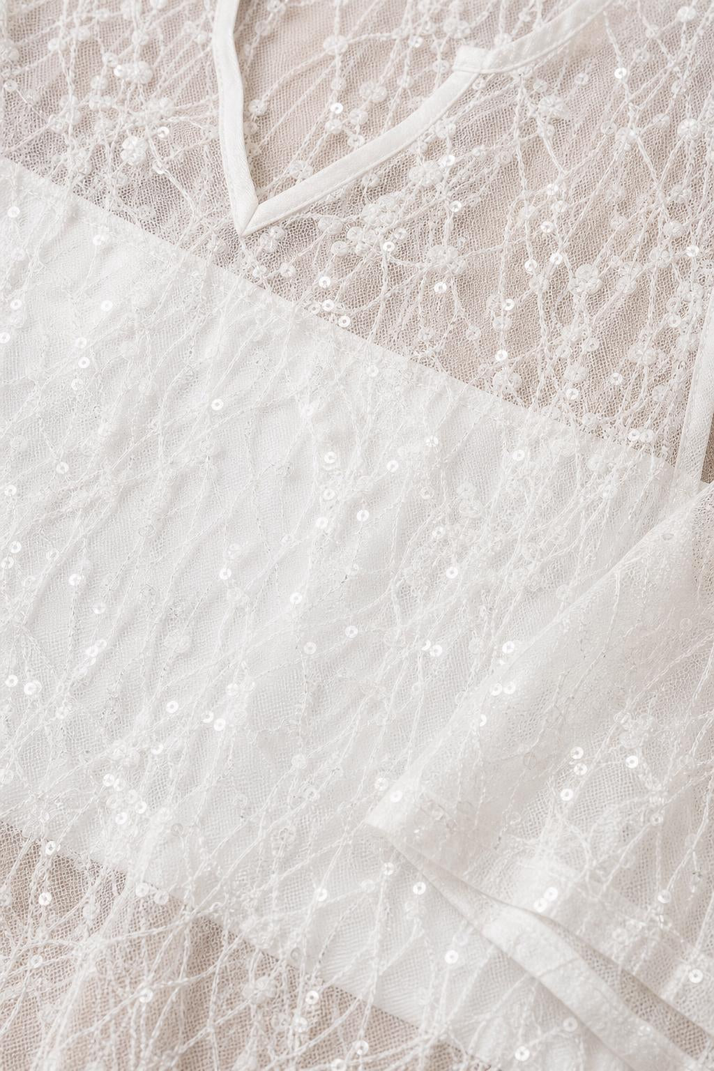 Close-up detail of white sequin lace fabric and neckline