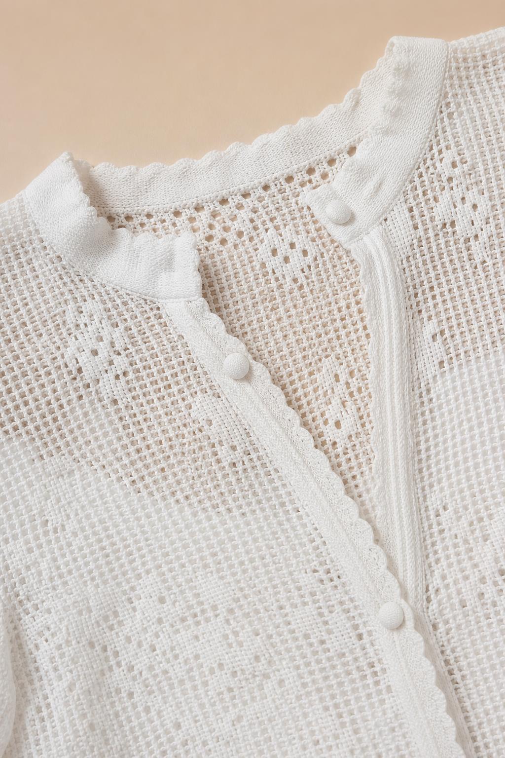 Close-up detail of white crochet lace knit texture and button closure