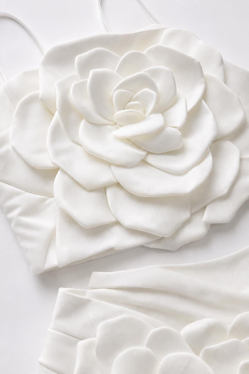 Close-up flat lay detail of white 3D fabric rose appliqué on top and skirt