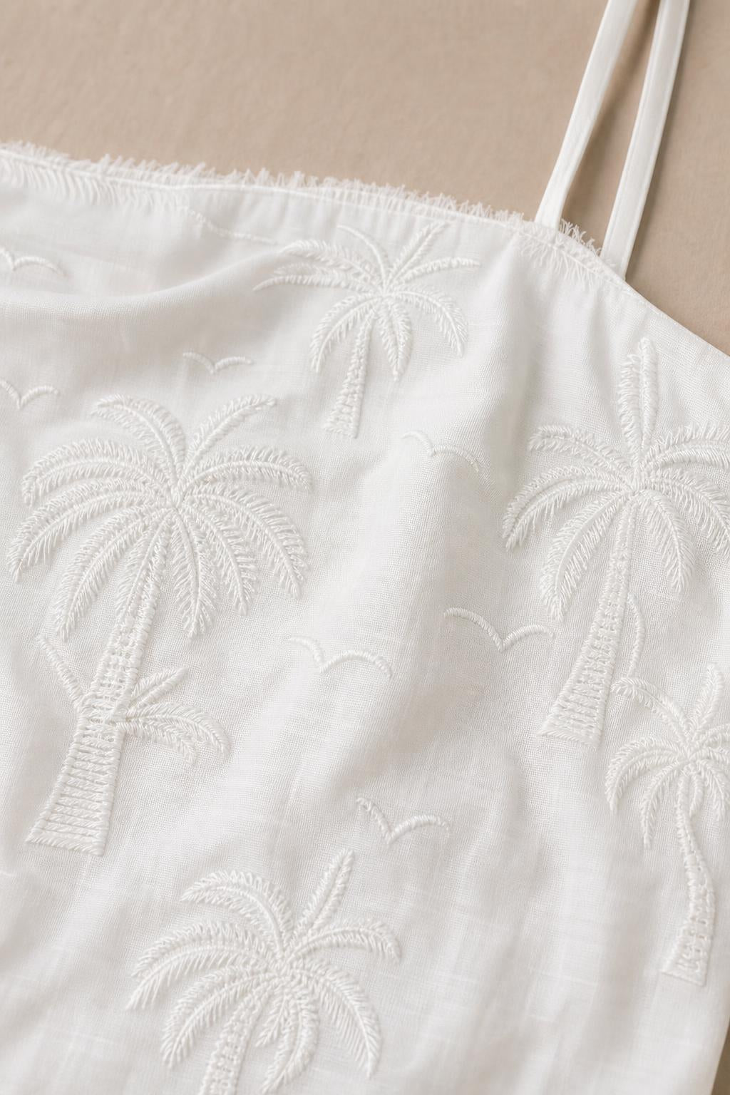 Close-up detail of white fabric with tonal palm tree embroidery