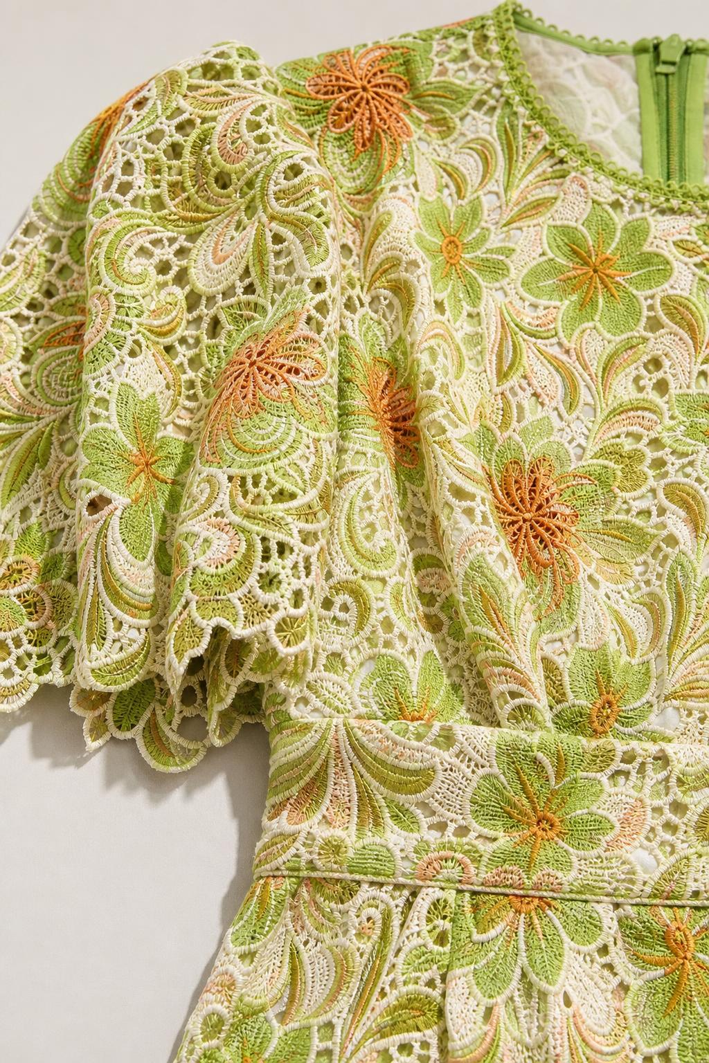 Close-up detail of green floral lace fabric and sleeve