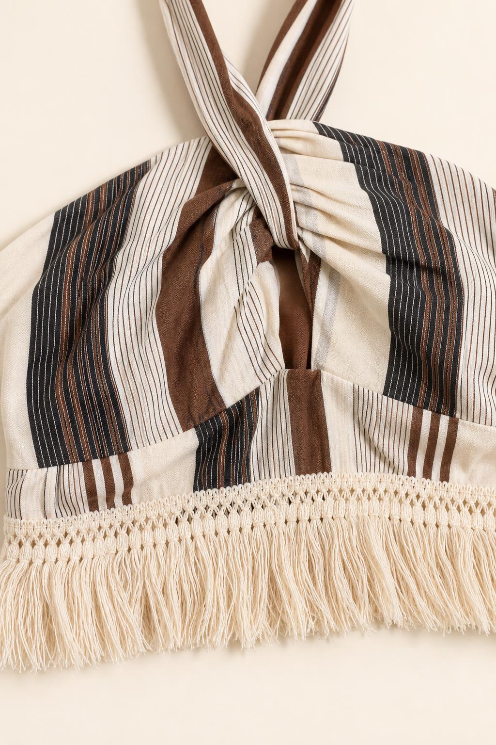 Close-up detail of halter twist and fringe trim on beige stripe dress