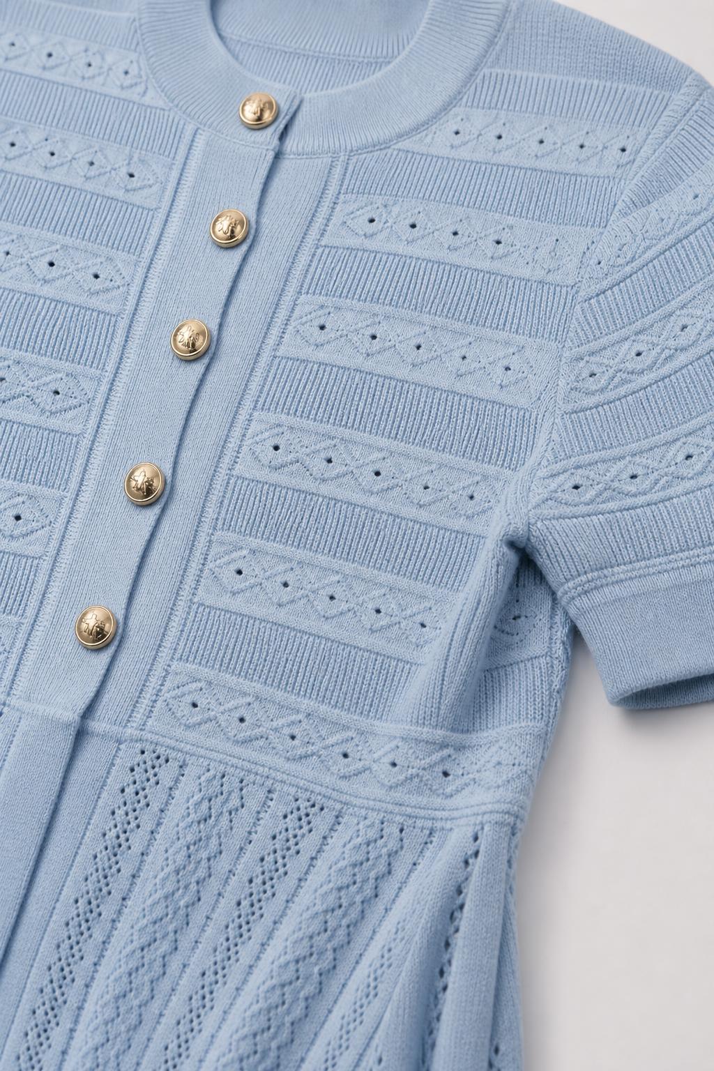 Close-up detail of buttons and knit pattern on light blue dress
