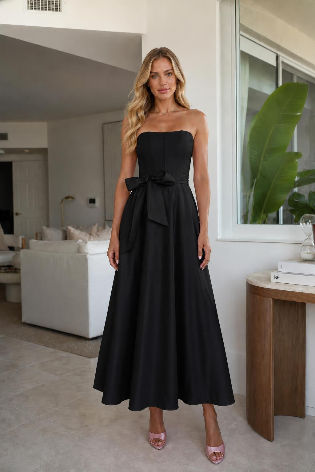 Model wearing black strapless bow waist midi dress