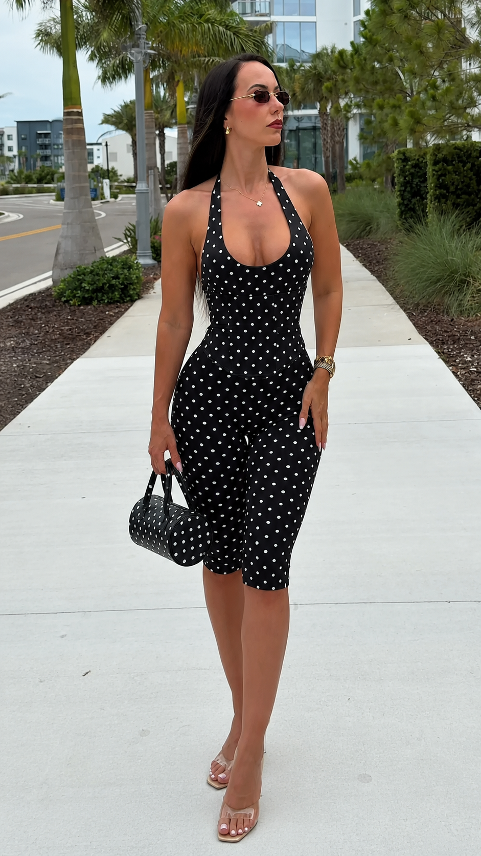 Front view of black polka dot halter biker jumpsuit with matching mini bag