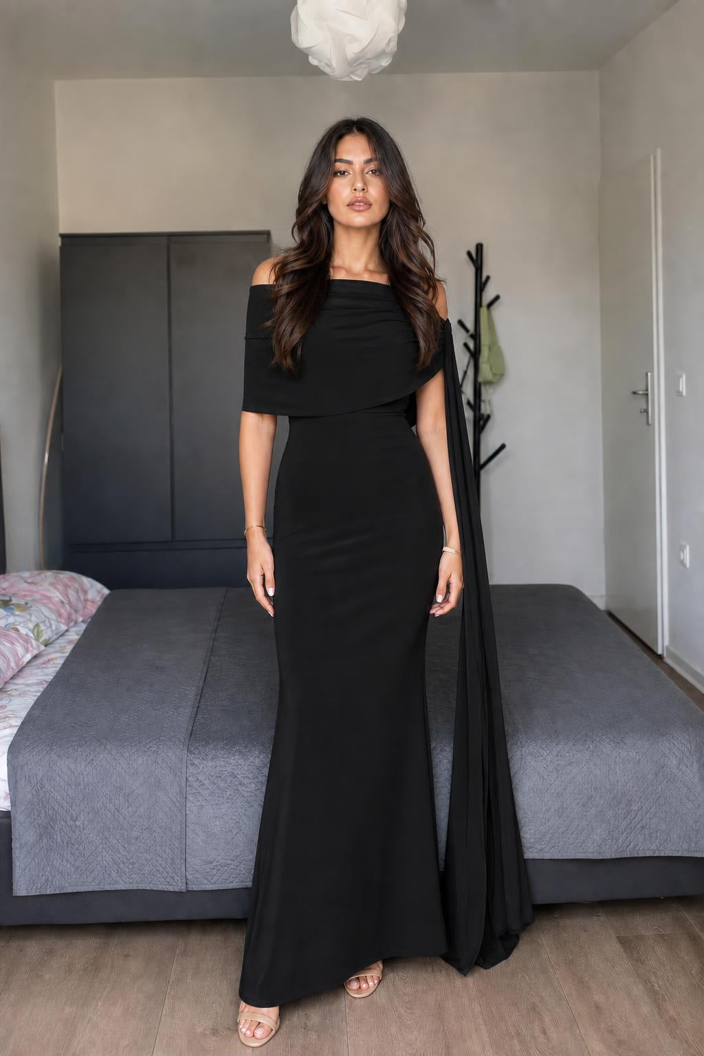 Model wearing black off-shoulder cape maxi dress