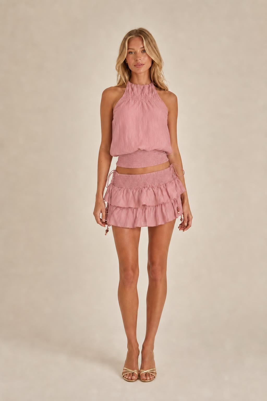 Model wearing pink halter top and ruffled mini skirt set
