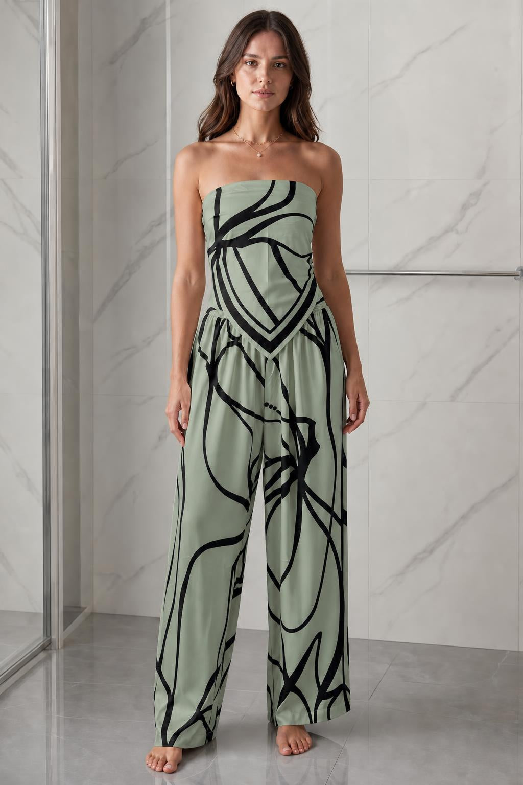 Woman wearing sage green and black abstract print strapless jumpsuit