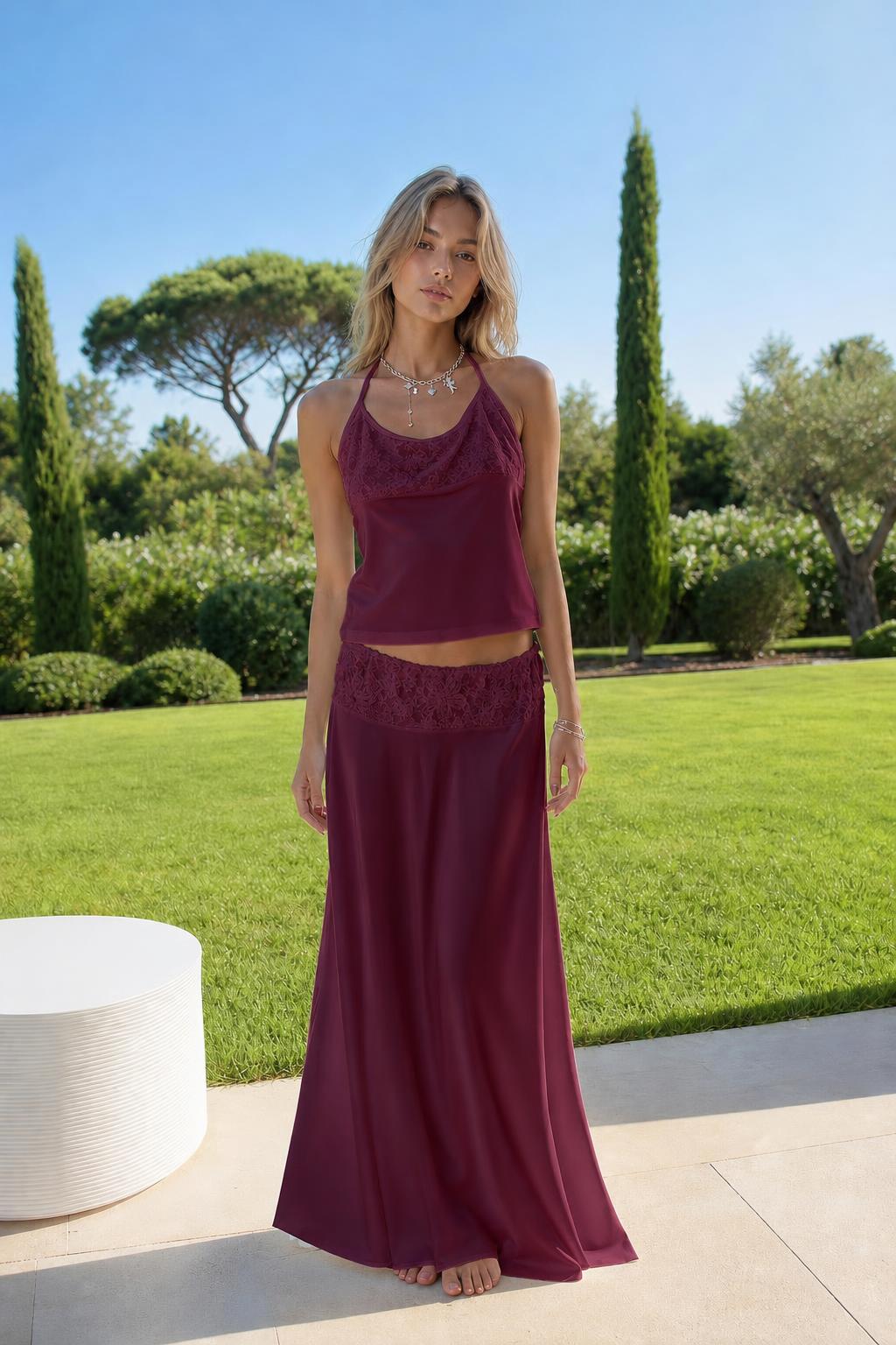 Model wearing burgundy satin halter top and lace skirt set