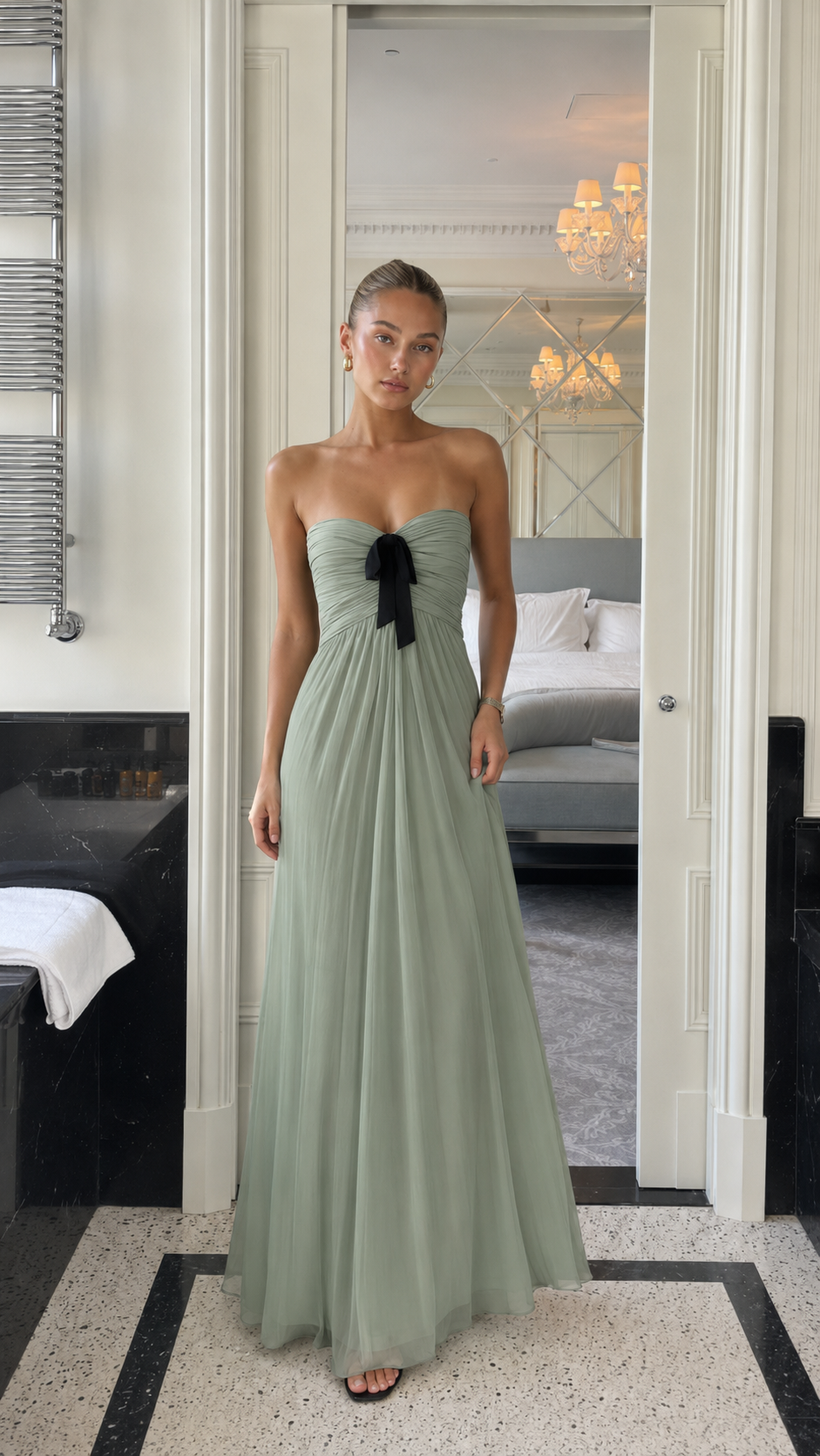 Front view of sage green strapless pleated maxi gown with black bow detail