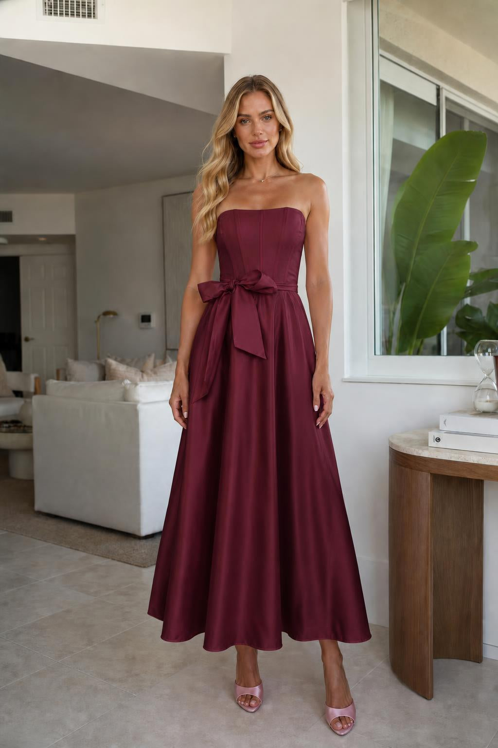 Model wearing burgundy strapless bow waist midi dress