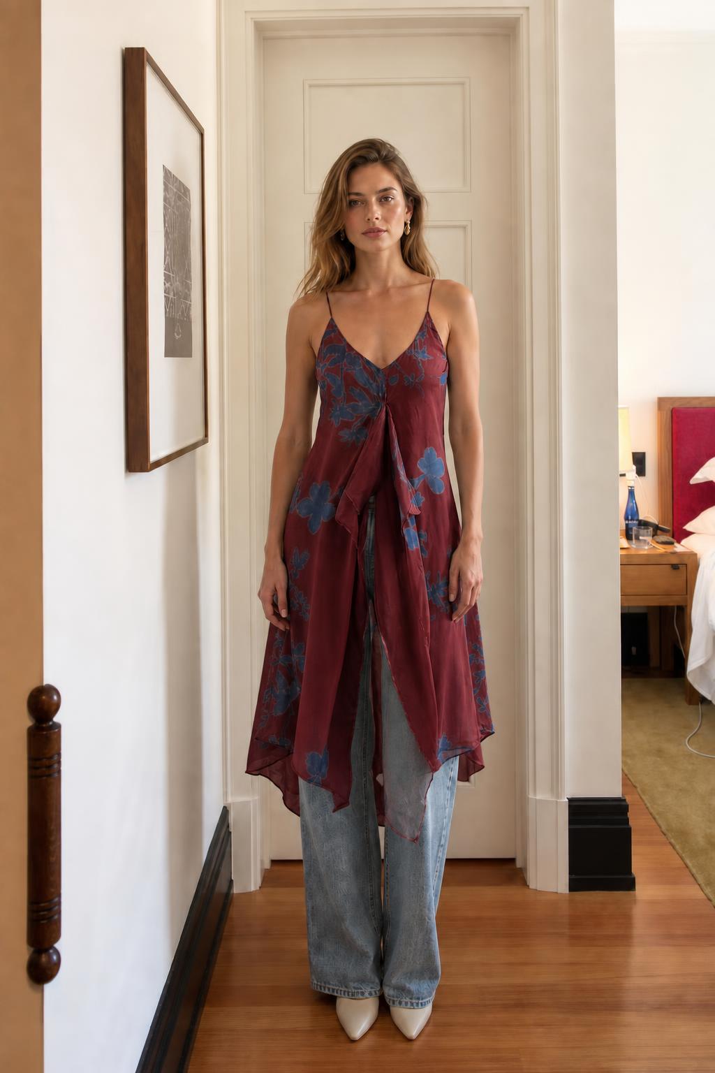 Model wearing burgundy floral cami dress over denim