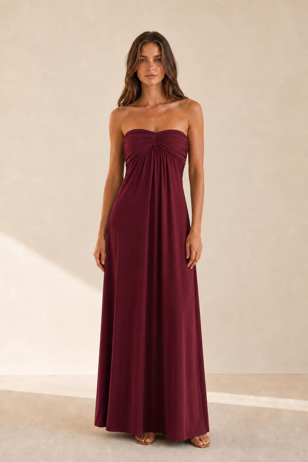 Woman wearing burgundy strapless ruched maxi dress front view