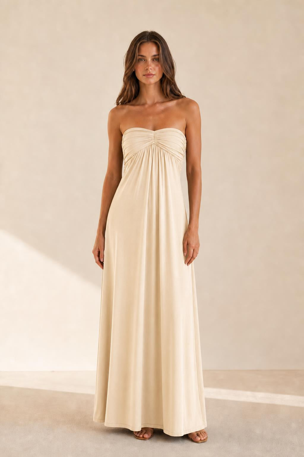 Woman wearing beige strapless ruched maxi dress front view