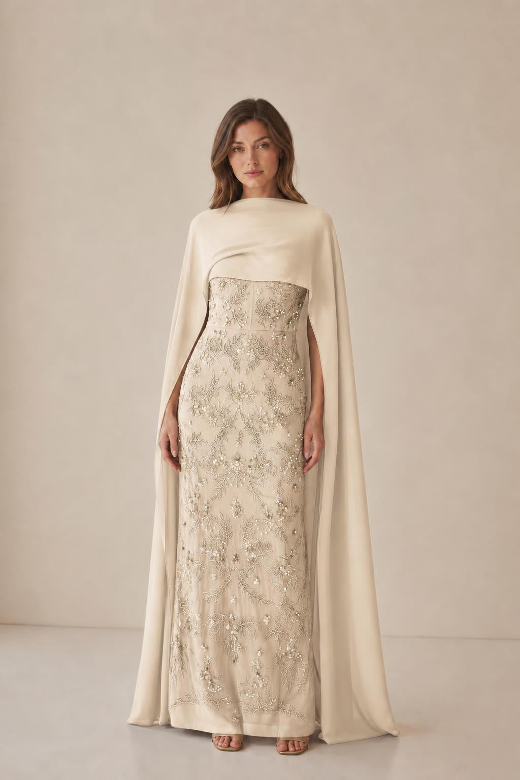 Model wearing champagne beaded dress with cape overlay